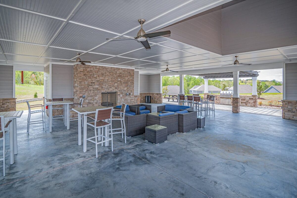 Spacious outdoor patio area featuring modern furniture and a stone fireplace, perfect for relaxation.